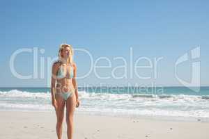 Woman in bikini walking on the beach in the sunshine
