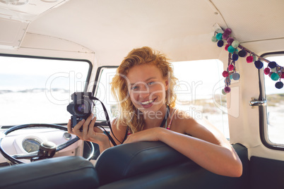 Woman with digital camera sitting in a camper van at beach