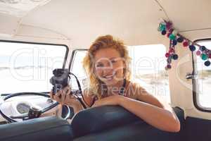 Woman with digital camera sitting in a camper van at beach