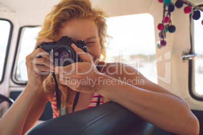 Woman taking photo with digital camera in camper van at beach