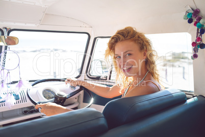 Woman looking at camera while driving a camper van at beach