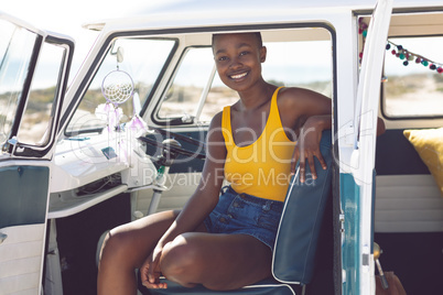 Woman looking at camera while sitting in a camper van at beach