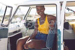 Woman looking at camera while sitting in a camper van at beach