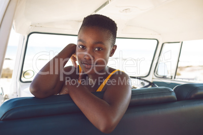 Woman looking at camera while sitting in a camper van at beach