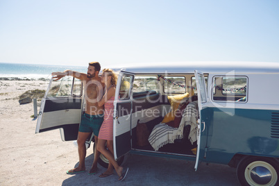 Couple standing near camper van at beach in the sunshine