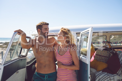 Couple talking with each other near camper van at beach in the sunshine