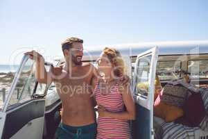 Couple talking with each other near camper van at beach in the sunshine