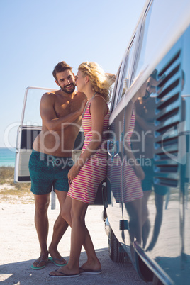 Couple talking with each other near camper van at beach in the sunshine