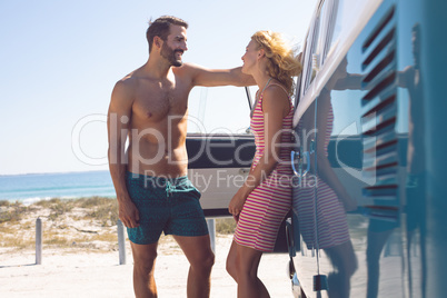 Couple talking with each other near camper van at beach in the sunshine