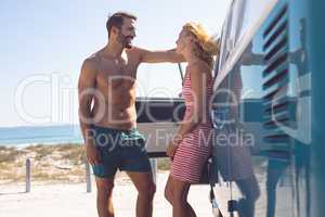 Couple talking with each other near camper van at beach in the sunshine