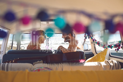 Couple talking with each other in camper van at beach