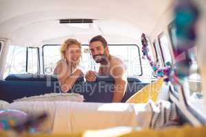 Couple looking at camera in camper van at beach