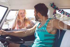 Man in camper van talking with woman while woman standing outside the van