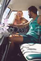 Man in camper van talking with woman while woman standing outside the van