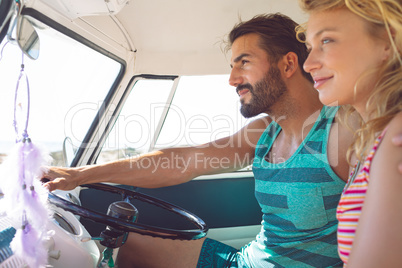 Couple sitting in front seat of camper van at beach