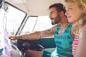 Couple sitting in front seat of camper van at beach