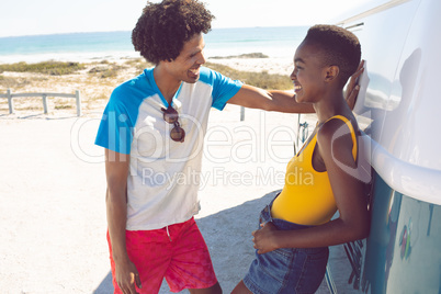 Couple talking with each other near camper van at beach in the sunshine