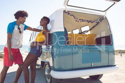 Couple talking with each other near camper van at beach in the sunshine