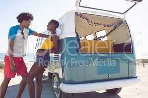 Couple talking with each other near camper van at beach in the sunshine