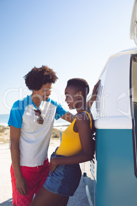 Couple talking with each other near camper van at beach in the sunshine