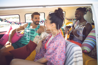 Group of friends having fun in a camper van at beach