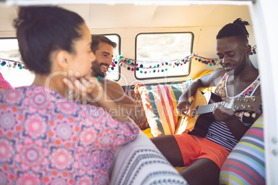 Group of friends having fun in a camper van at beach