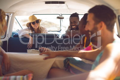 Group of friends having fun in a camper van at beach