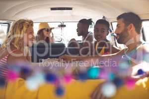 Group of friends talking with each other in a camper van at beach