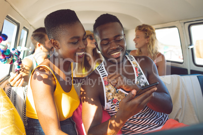 Friends discussing over mobile phone in camper van at beach