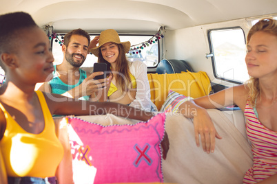 Group of friends having fun in a camper van at beach