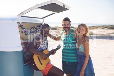 Group of friends having fun together near camper van at beach