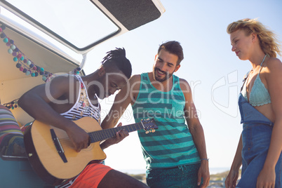 Group of friends having fun together near camper van at beach