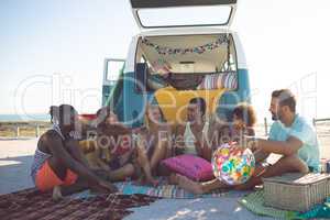 Group of friends interacting with each other near camper van at beach