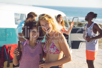 Group of friends having fun near camper van at beach