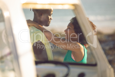 Couple embracing each other near camper van at beach