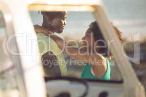 Couple embracing each other near camper van at beach