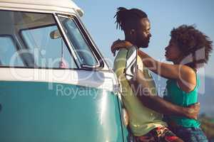 Couple embracing each other near camper van at beach