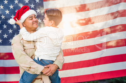 Hispanic Male Soldier Wearing Santa Cap Holding Mixed Race Son In Front of American Flag