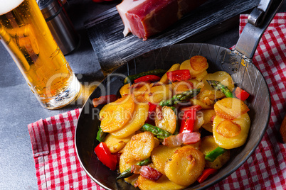 Fried potatoes with smoked bacon, green asparagus and paprika.