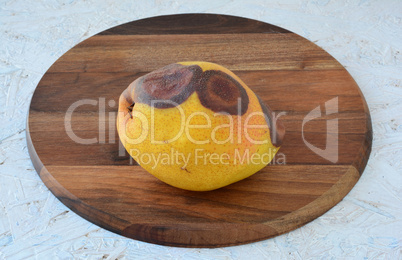 Rotten pear on a chopping board
