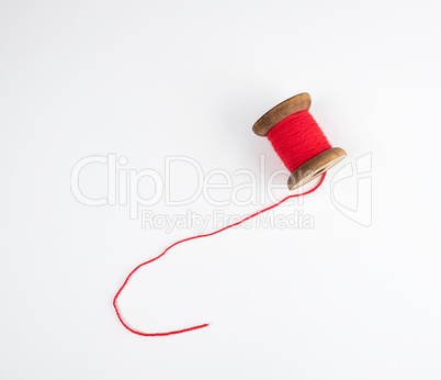 wooden bobbin with red wool threads on a white background