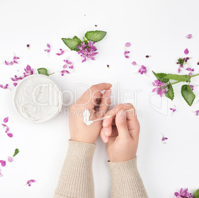 two female hands and a jar with thick cream and pink flowers