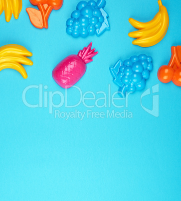 multicolored plastic toys fruits on a blue  background