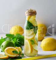 lemonade with lemons, mint leaves, lime in a glass bottle