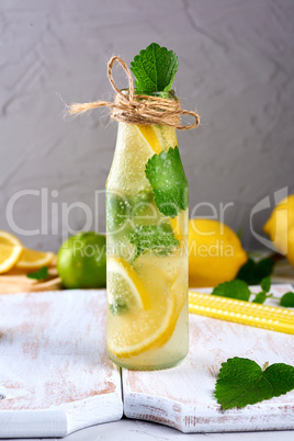 lemonade with lemons, mint leaves, lime in a glass bottle
