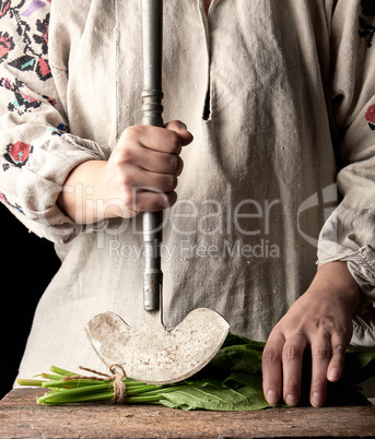 woman in a gray dress is cutting leaves of fresh sorrel