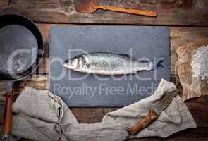 fresh whole sea bass fish on a black board