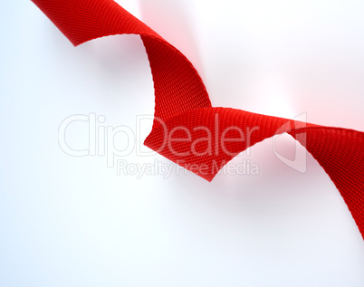 twisted red textile belt with a coarse fiber on a white backgrou
