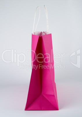 pink paper shopping bag with a handle on a white background