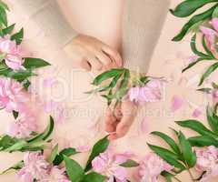 hands of a young girl with smooth skin and a bouquet of pink peo